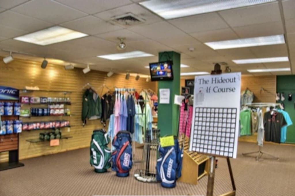 Un magasin de détail où l’on trouve des étagères remplies d’articles de sport et des portants chargés de vêtements.