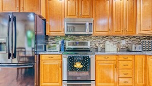 A kitchen with wooden cabinets, stainless steel appliances, and a tiled backsplash.