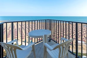 A balcony with a view of a beach with rows of umbrellas and chairs. - Hotel Mondial (Jesolo)