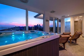 Ein Whirlpool mit Blick auf die Stadt, einer Glastür und Holzstühlen.
