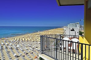 Ein Balkon mit Blick auf einen belebten Strand und das Meer.