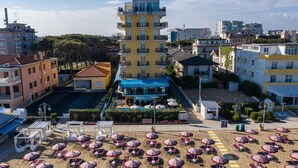 Un hôtel doté d’un bâtiment principal, d’un espace piscine et d’une plage avec des parasols.