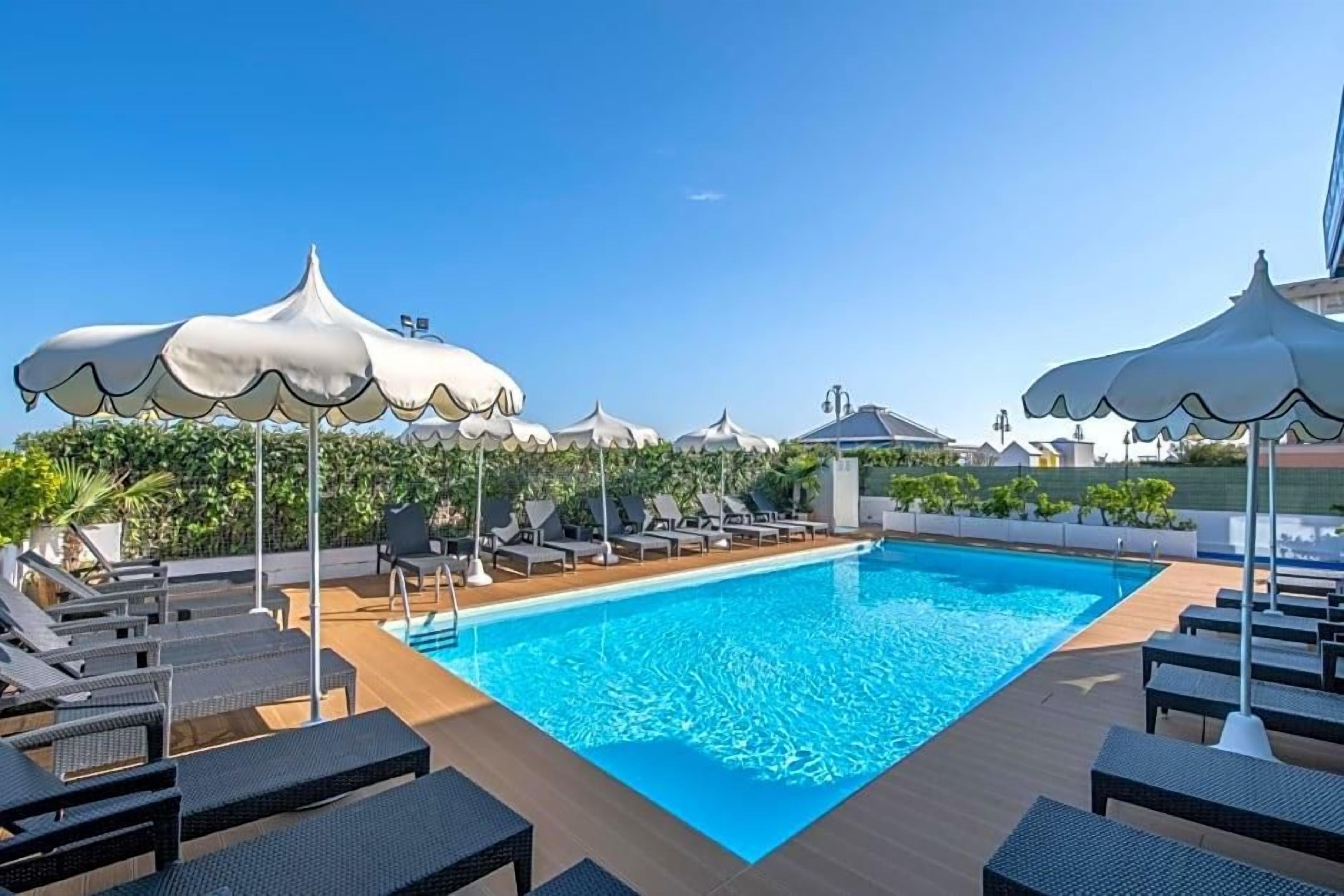 A swimming pool with lounge chairs and umbrellas.