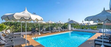 A swimming pool with lounge chairs and umbrellas.