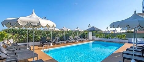 A swimming pool with lounge chairs and umbrellas.