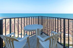 A balcony with a view of a beach with rows of umbrellas and chairs. - Hotel Mondial (Jesolo)