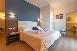 A hotel room with a bed, bedside table, and a desk with a chair. - Hotel Mondial (Jesolo)