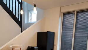 Una cocina moderna con una mesa de madera y cuatro sillas, un refrigerador negro y una ventana con persianas.