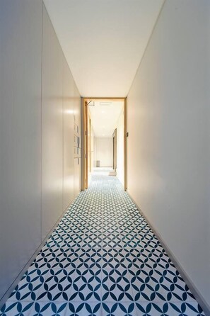 Un pasillo con piso estampado y vista a otra habitación.
