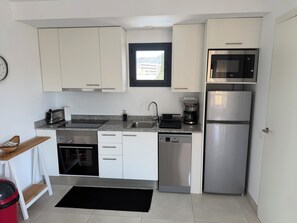 A modern kitchen with white cabinets, stainless steel appliances, a built-in microwave, and a coffee maker. - Modern apartment in superb residence with PISCINE-3 Min PLAGE ROSAS- Clim-Wifi (Roses)