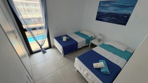 A hotel room with two beds, a window with a view of a pool, and a painting on the wall. - Modern apartment in superb residence with PISCINE-3 Min PLAGE ROSAS- Clim-Wifi (Roses)