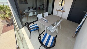 A balcony with a dining table, chairs, and a glass door leading to an indoor area. - Modern apartment in superb residence with PISCINE-3 Min PLAGE ROSAS- Clim-Wifi (Roses)