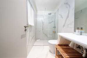 Ein modernes Badezimmer mit einer Duschkabine, einer weißen Toilette und einem hölzernen Waschtisch mit Spiegel.