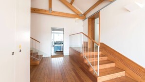 Eine Holztreppe mit Glastrennwand führt zu einem Schlafzimmer.