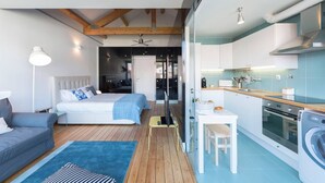 Ein modernes Schlafzimmer mit einem großen Bett, einem kleinen Schreibtisch und einer Küchenzeile.
