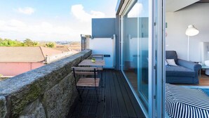 Un balcon avec une table et des chaises, un canapé et une grande fenêtre donnant sur la ville.