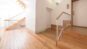 Une pièce spacieuse dotée d’un plancher en bois, d’un escalier avec des rampes en métal et d’une porte avec une poignée.