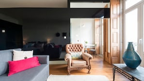 Un salon moderne avec un canapé gris, un fauteuil marron et une table à manger en bois.