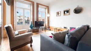 Un salon avec un canapé, un téléviseur et une grande fenêtre.