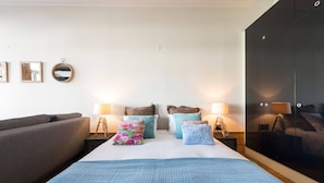 Une chambre à coucher comprenant un lit, deux tables de chevet, une commode, une armoire et un canapé gris.