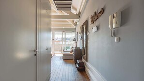 A hallway with a wooden floor, a white door, and a wall-mounted telephone. - Oporto LightHouse Apartment by DA'HOME (Porto)