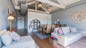 A spacious living area with a high ceiling, wooden flooring, and a dining set. - Oporto LightHouse Apartment by DA'HOME (Porto)