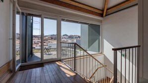 A room with a wooden floor, a staircase with metal railings, and large windows offering a view of the outside. - Oporto LightHouse Apartment by DA'HOME (Porto)
