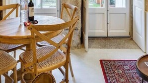 Un comedor rústico con una mesa y sillas de madera, una botella de vino y un tapete rojo estampado.