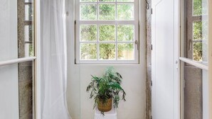 A bathroom with a large window, a potted plant, and a shower curtain. - Jardins da Muralha Suite Downtown by DA'HOME (Porto)