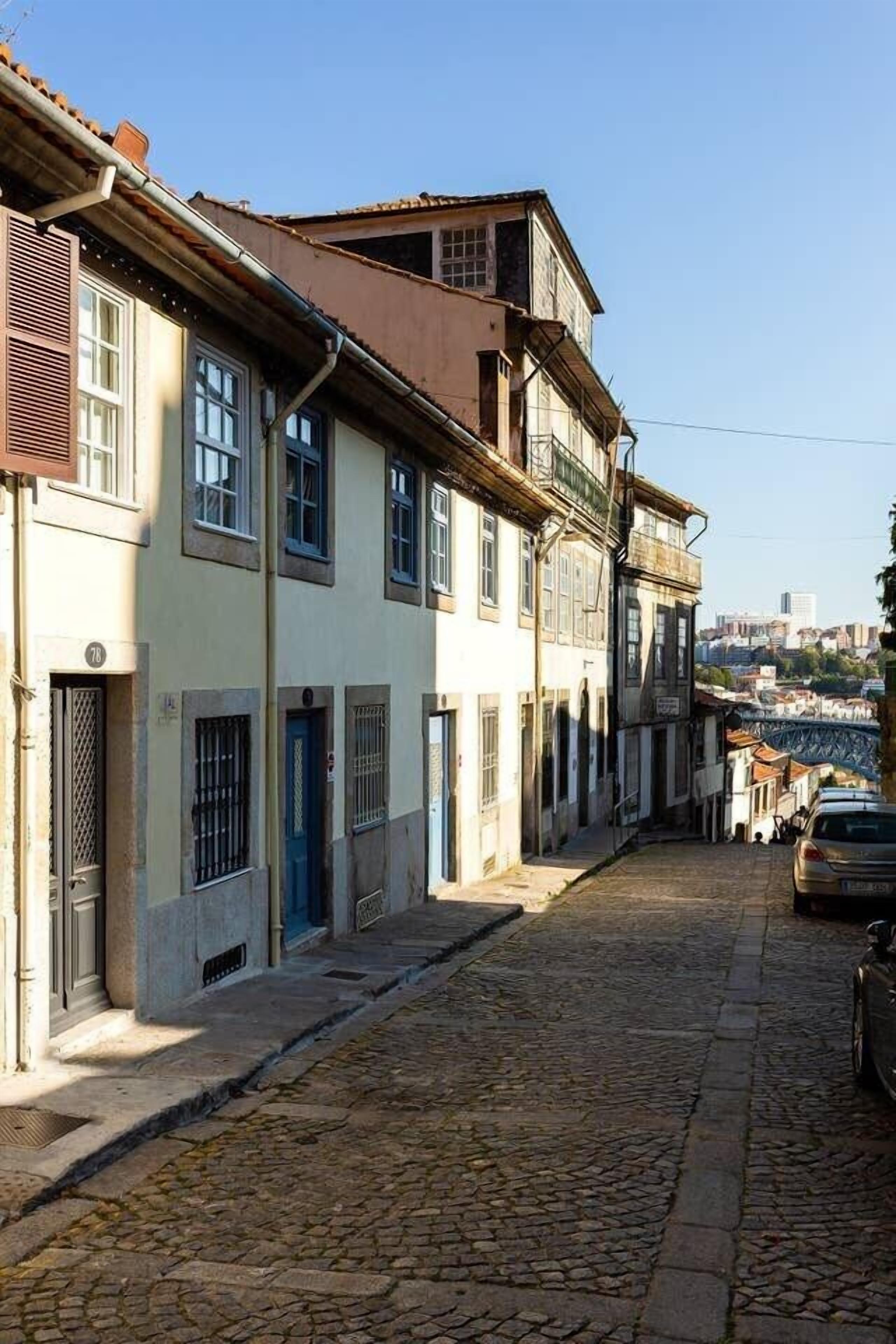 Une ruelle étroite pavée, bordée de bâtiments historiques, où se côtoient des immeubles d’habitation et des commerces.