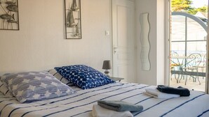 En snyggt bäddad säng med randigt sänglinne, en blå och vit mönstrad kudde och en hopvikt handduk.
