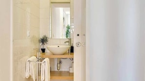 Ein Badezimmer mit einem weißen Waschbecken, einem Spiegel, einem Handtuchhalter und einer Topfpflanze.