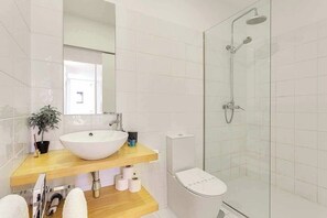 Une salle de bain moderne avec un grand lavabo blanc, des toilettes et une douche à parois de verre.