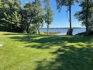 A grassy area with trees and a body of water in the background.