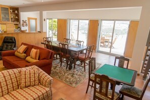 A spacious living area with a sofa, a dining table, and a pool table.