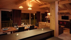 A wooden interior with a dining area, a bar, and a living space. - Chalet Poudreuse (Morzine)
