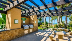 An outdoor patio with a barbecue grill, stone walls, and wooden tables and chairs.
