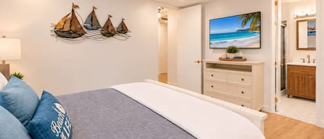 Quarto com cama, ventoinha no teto, televisão fixada na parede e decoração náutica.