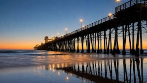 A pier extending into the water with a building at the end, reflecting on the calm surface.