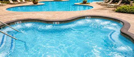 A multi-tiered pool area with lounge chairs and palm trees.