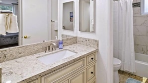 A bathroom with a sink, mirror, toilet, and shower curtain.