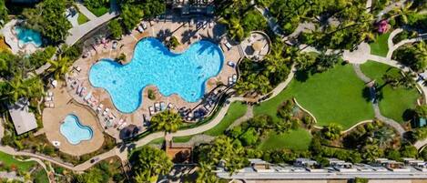 An aerial view of a hotel with a central swimming pool, surrounded by landscaped areas and pathways.