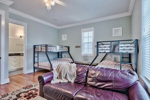 Un dormitorio con literas, un sofá de cuero, una ventana y una puerta que da a un baño.