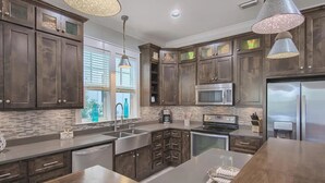 A modern kitchen with dark wood cabinets, stainless steel appliances, and a large island.