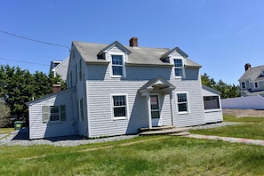 A two-story house with a front porch, a chimney, and a small attached garage.