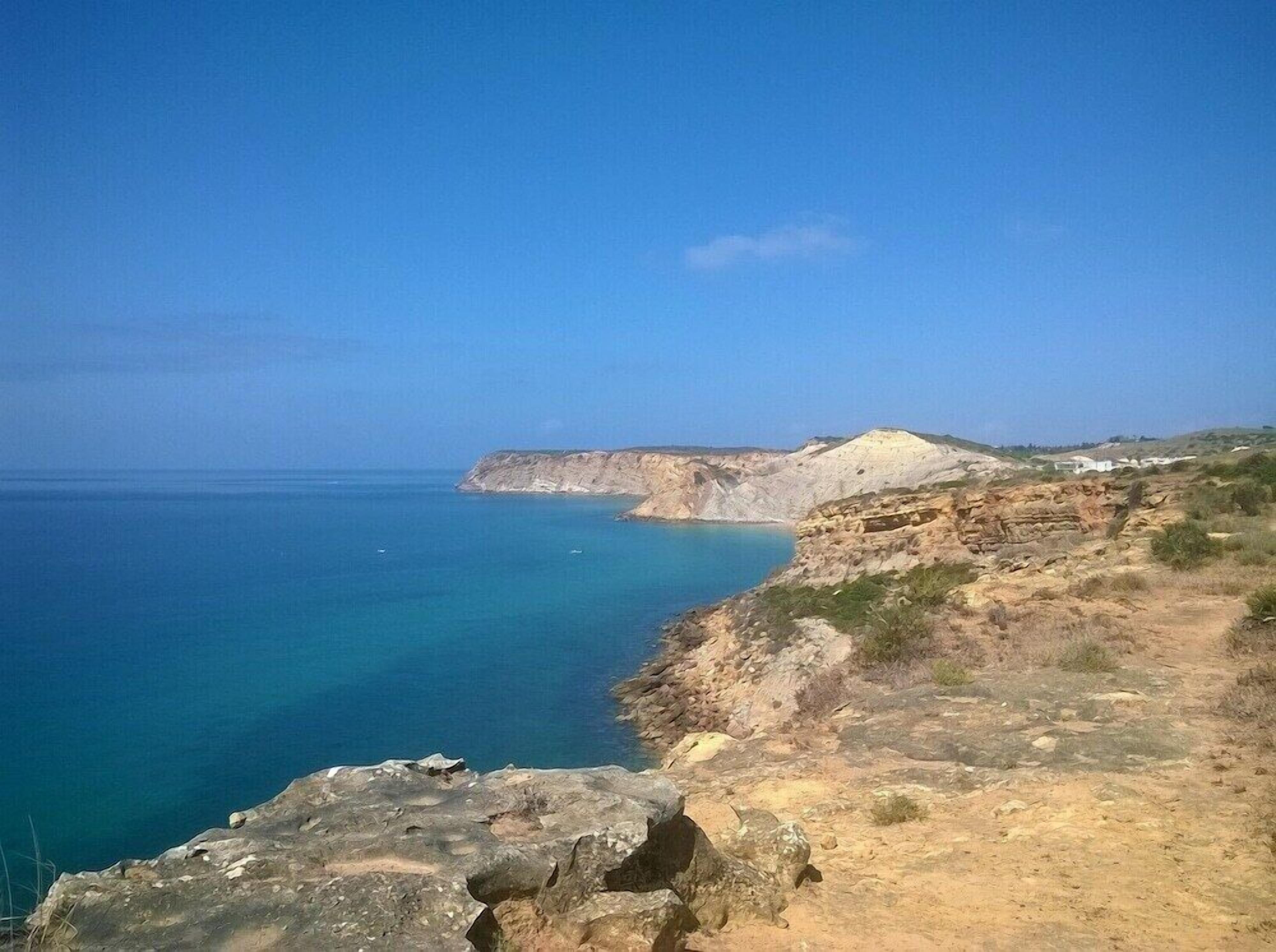 A coastal landscape with a clear view of the sea and rocky terrain.