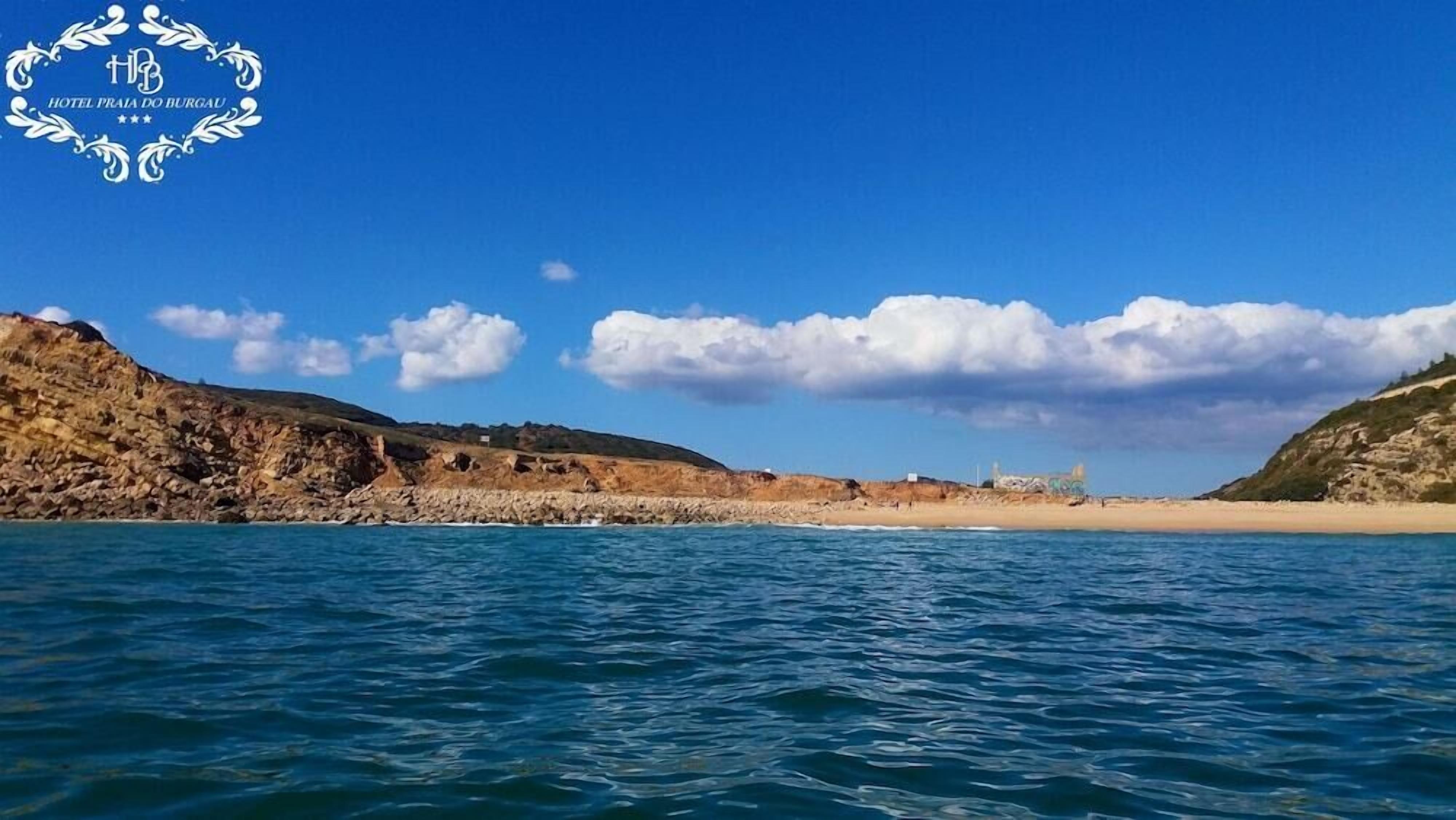 Vista costera con costa rocosa, una playa arenosa y cielo azul despejado.