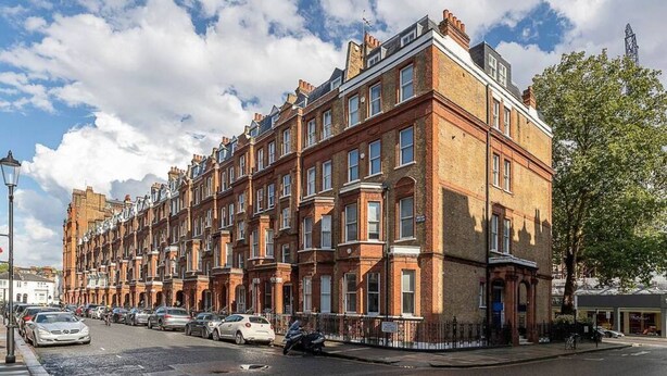 A row of red brick terraced houses with multiple windows and a street in front. - Lovely flat in Chelsea (London)