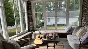 Ein gemütliches Zimmer mit Steinwand, gepolstertem Sitzplatz, einer Gitarre und einem Schachbrett.