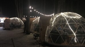 Schneeweiße Iglus mit Lichterketten in einer verschneiten Winterlandschaft.